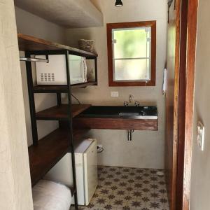 a small kitchen with a sink and a microwave at Pousada Quintal da Prosa in São Francisco Xavier