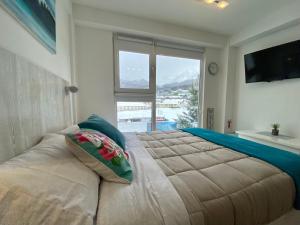 een slaapkamer met een groot bed en een groot raam bij AIRES DEL SUR in Ushuaia