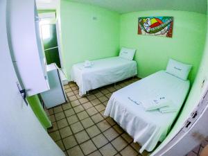 duas camas num quarto com paredes verdes em Pousada Litoral em Porto de Galinhas