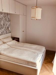 a white bed in a bedroom with a lamp at Apartament Family Premium - Baltic Sun Sztutowo in Sztutowo