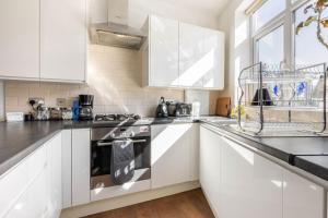 a kitchen with white cabinets and a stove top oven at Spacious 2 bed Apartment with FREE PARKING for 2 cars and underground station Zone 2 for quick access to Central London up to 8 guests in London
