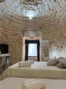 een slaapkamer met 2 bedden en een stenen muur bij Il trullo di Mattia in Noci