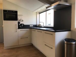 a kitchen with white cabinets and a black counter top at T Skûttegat in Hollum