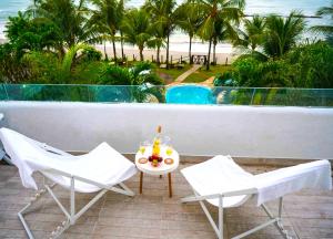 un balcón con 2 sillas y una mesa con bebidas. en As Coloridas, en Praia dos Carneiros