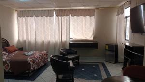 een hotelkamer met een bed, een stoel en een raam bij Hotel Sol de Oro in Guayaquil