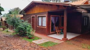 Cabaña de madera con una silla en el patio en Voces De La Selva Misionera en Puerto Iguazú