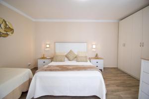 1 dormitorio blanco con 2 camas y 2 mesitas de noche en Casa Los Titos en Arriate