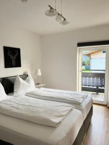 ein großes weißes Bett in einem Schlafzimmer mit Fenster in der Unterkunft Peters Panoramaappartment in Piesendorf
