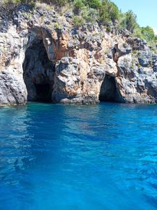 a cave in the side of a cliff with blue water at B&b Anna's home in Marina di Camerota