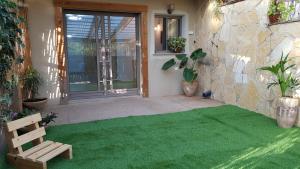 a patio with a green carpet in front of a house at Rosewood in Kefar Weradim