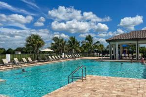 a swimming pool with chairs and people in the water at Brand New Fort Myers Townhome Community Pool in Fort Myers