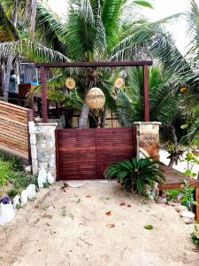 a wooden gate in front of a house with palm trees at Hotel Bendita Luna Salchi in Cuatunalco