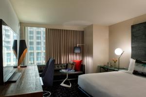 ロサンゼルスにあるキンプトン ホテル パロマー ロサンゼルス ビバリーヒルズのベッドとデスクが備わるホテルルームです。