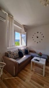 uma sala de estar com um sofá e um relógio na parede em Apartment Pemper - Self check in and check out em Otočac