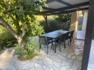 a table and chairs on a patio with a tree at Les Arches - Pardigon in La Croix-Valmer