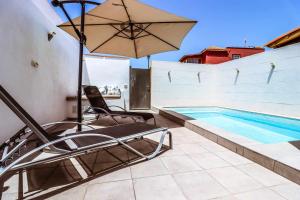 - une terrasse avec une chaise et un parasol à côté de la piscine dans l'établissement Rentaliday Estrella Marazul, à Las Galletas