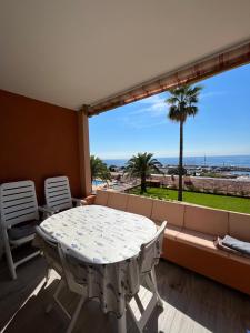 a table and chairs on a balcony with a view of the ocean at Appartement avec vue mer et piscine in Théoule-sur-Mer