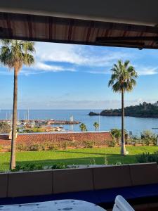 a view of the ocean from a patio with palm trees at Appartement avec vue mer et piscine in Théoule-sur-Mer