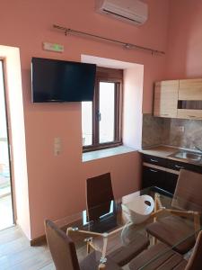a kitchen with a dining table and a tv on the wall at Lindos Villa Euphoria in Líndos