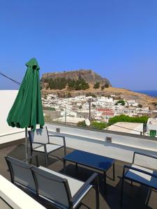 a patio with a green umbrella and chairs and a table at Lindos Villa Euphoria in Lindos