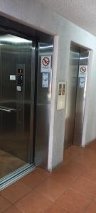 two elevator doors in a building with no smoking signs at Acogedor Apartamento, rodeado de Naturaleza y Mar. in Puerto Montt