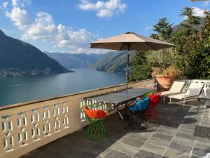 un tavolo e sedie con ombrellone su un balcone di Lake Como Villa Ines Apartment a Faggeto Lario