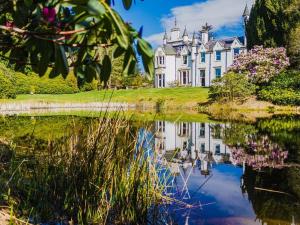 a large white house with a reflection in a body of water at Dalnaglar Castle in Blairgowrie
