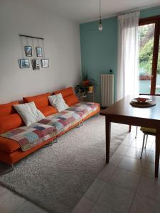 pomarańczowa kanapa w salonie ze stołem w obiekcie Private Room near Treviso "Mira" w mieście Silea