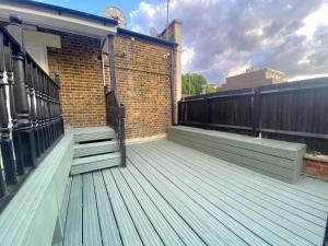 a wooden deck on a building with a brick wall at Mandarin Apartment in London