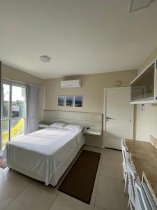 a bedroom with a white bed and a television at Pousada Recanto do Neca in Florianópolis