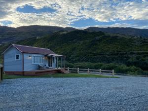 a small house with a porch and mountains in the background at Rose Creek Cottage in Cromwell