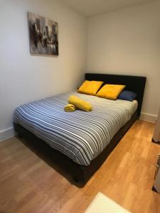 Una cama con dos almohadas amarillas encima. en City Sparrow Pad 6 en Londres