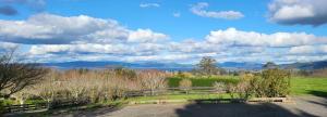 a field with a fence and a view of the mountains at Hamurana Home with a View in Rotorua