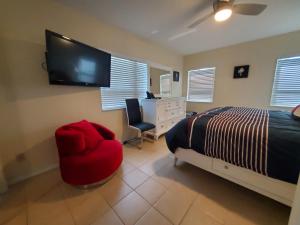 een slaapkamer met een bed, een stoel en een televisie bij Ocean Side Resort - updated Villa in Hillsboro Beach