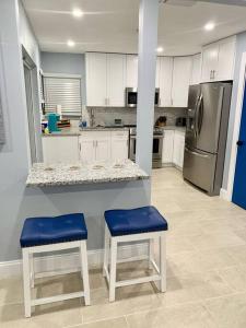 a kitchen with a counter and two blue stools at Home in West Palm Beach with Heated Pool in West Palm Beach