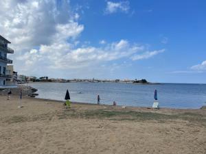 a beach with people on the sand and the water at Appartamento Marzamemi in Marzamemi