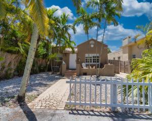 a house with palm trees and a white fence at Bike to Beach-Spacious With Patio BBQ & Game Room (Pet-Friendly) in Hallandale Beach