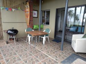 a patio with a table and chairs and a grill at Ocean Rush Dolphin in Zinkwazi Beach