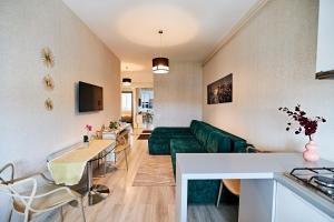 CityLife Apartments في ياش: غرفة معيشة مع أريكة خضراء وطاولة