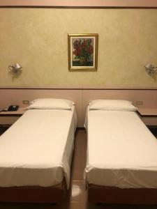 2 camas en una habitación con una foto en la pared en Le Petit Hotel, en Turín