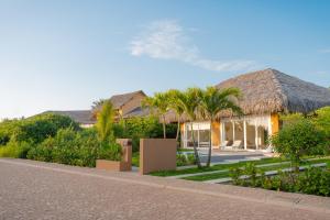 una casa con techo de paja y palmeras en Tanusas Retreat & SPA, en Puerto Cayo