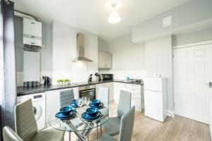 een keuken met een glazen tafel met blauwe gerechten erop bij Sheffield Contractors Stays- Sleeps 6, 3 bed 3 bath house. Managed by Chique Properties Ltd in Brightside