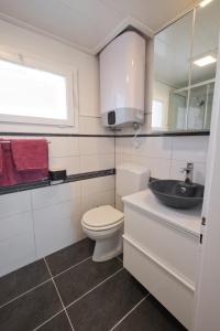a white bathroom with a toilet and a sink at Lake Getaway Apartment with Private entrance, right on the Lake Constance cycle path, barbecue area, free wifi, Netflix and free bikes in Salmsach