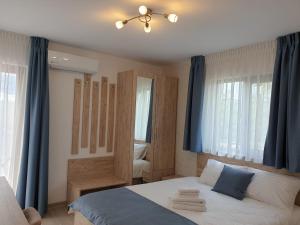 a bedroom with a large bed with blue curtains at Pensiunea Lotus Corbu in Corbu +81 photos