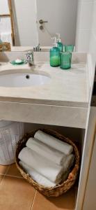 een badkamer met een wastafel en een mand met handdoeken bij Thelighthouse Porto Santo in Porto Santo