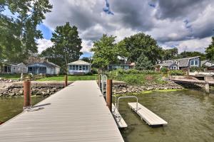 a dock with a boat on a river with houses at Lake Erie Waterfront Home with Sunroom and Yard! in Erie