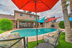 een zwembad met 2 stoelen en een parasol bij Relaxing Phoenix House with Hot Tub and Heated Pool! in Phoenix