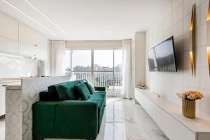 a green couch in a living room with a large window at Suite Verano Stay in Rio de Janeiro