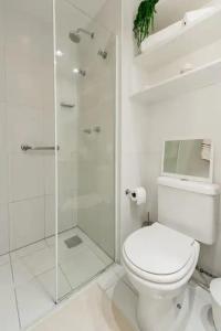 a white bathroom with a toilet and a glass shower at Suite Verano Stay in Rio de Janeiro