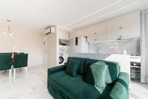 a living room with a green couch in a white room at Suite Verano Stay in Rio de Janeiro